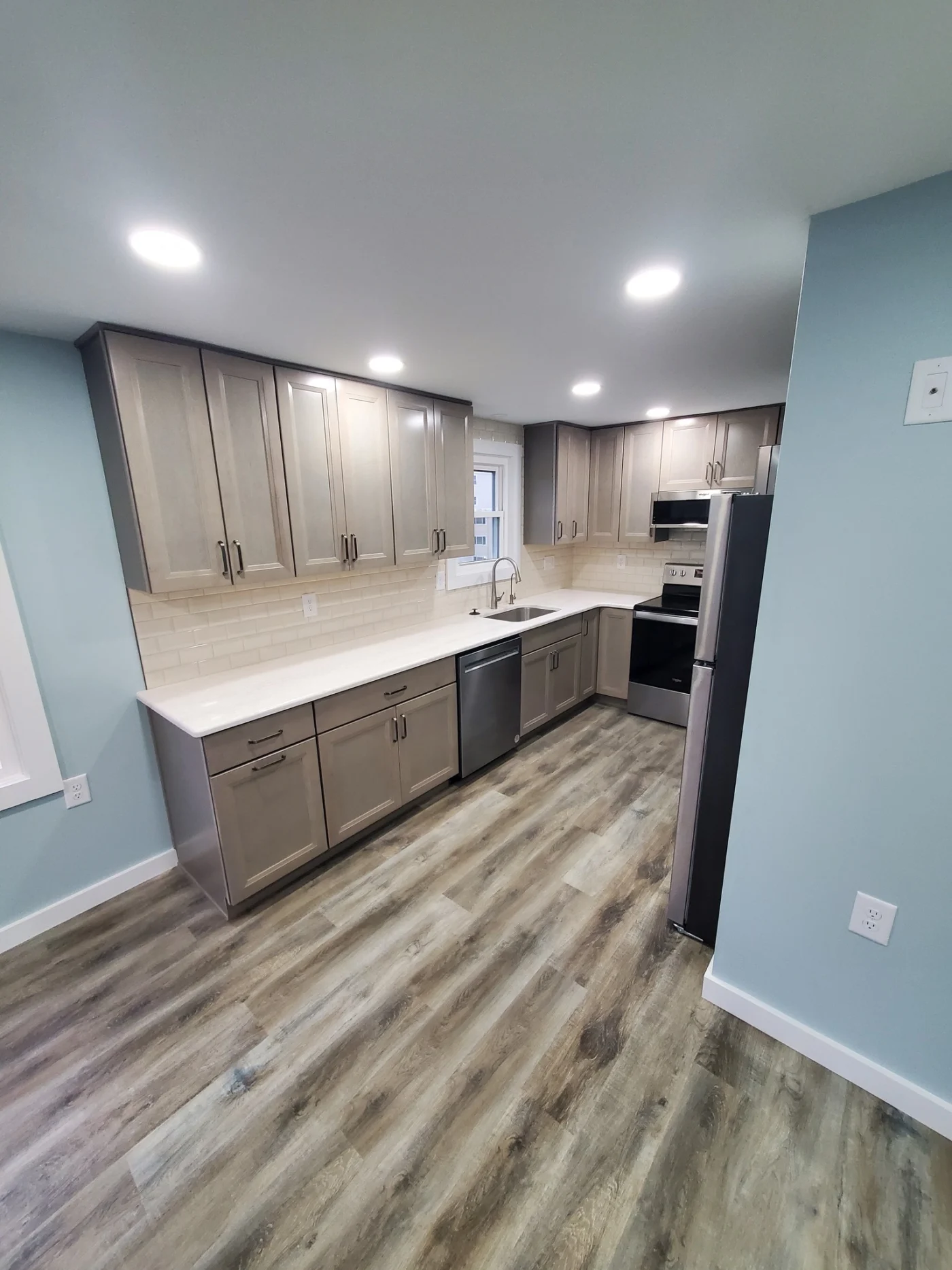 An image of a small residential bathroom in an Ocean Pines, MD home, after a 5-day bathroom remodel with Mast Contracting, showing new white paint, new tub/shower combo with both rainfall and handheld showerheads, new cabinetry, toilet, countertops, lighting, and flooring.