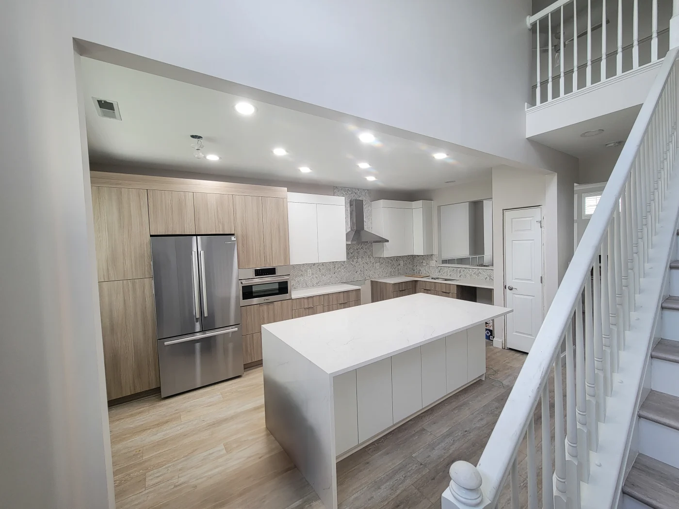 Kitchen with white island, wood and white cabinets, and a silver refrigerator and freezer