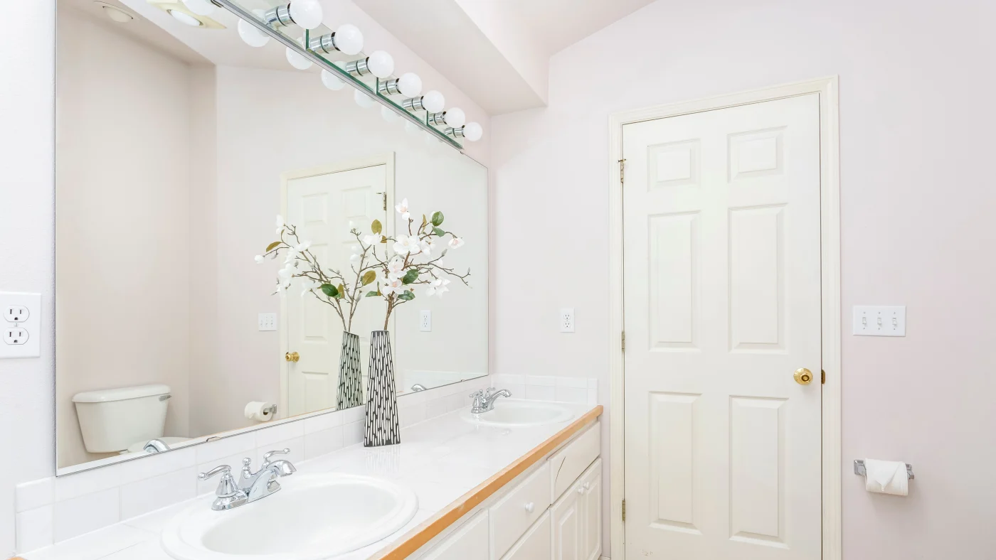 White Bathroom Interior With Double Sink Vanity And Vaulted Ceiling. White Bathroom Interior With Double Sink Vanity And Vaulted Ceiling.