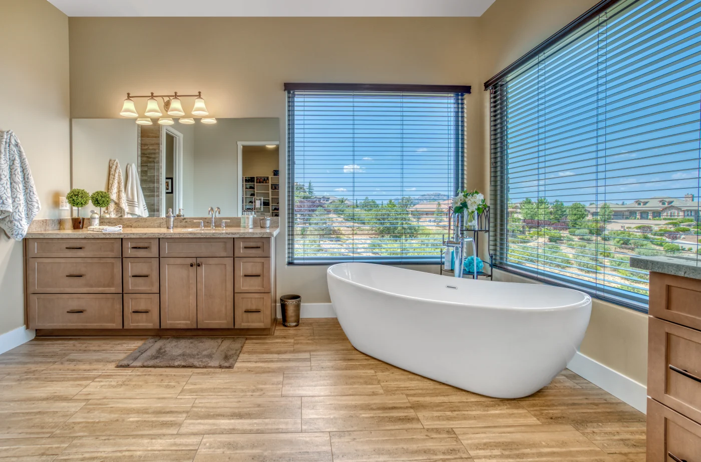 Wood floors, wood cabinets with beige walls and free form white tub in bathroom