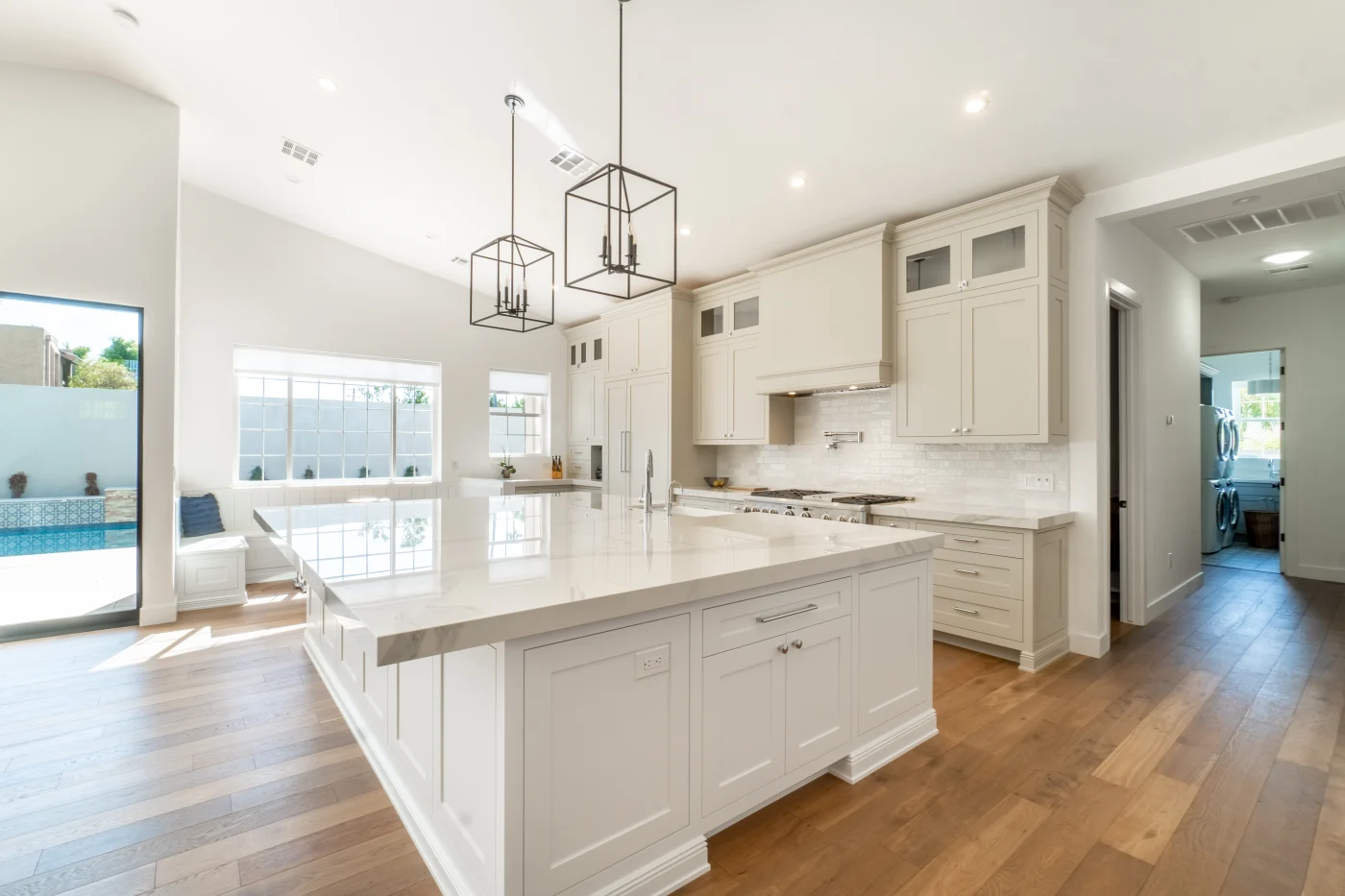 Updated kitchen with white cabinets, wood floor, and extra large island with white countertop