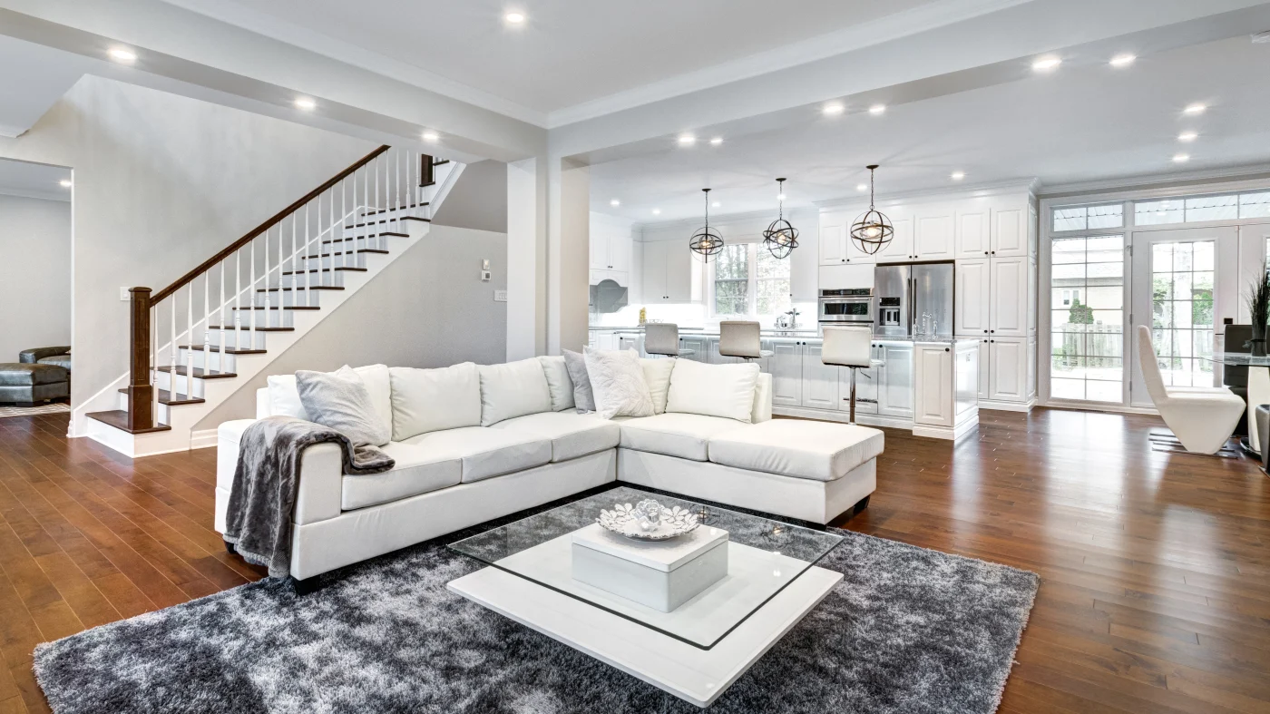 Open-concept living room and kitchen with dark hardwood flooring and white cabinets, walls, and ceilings