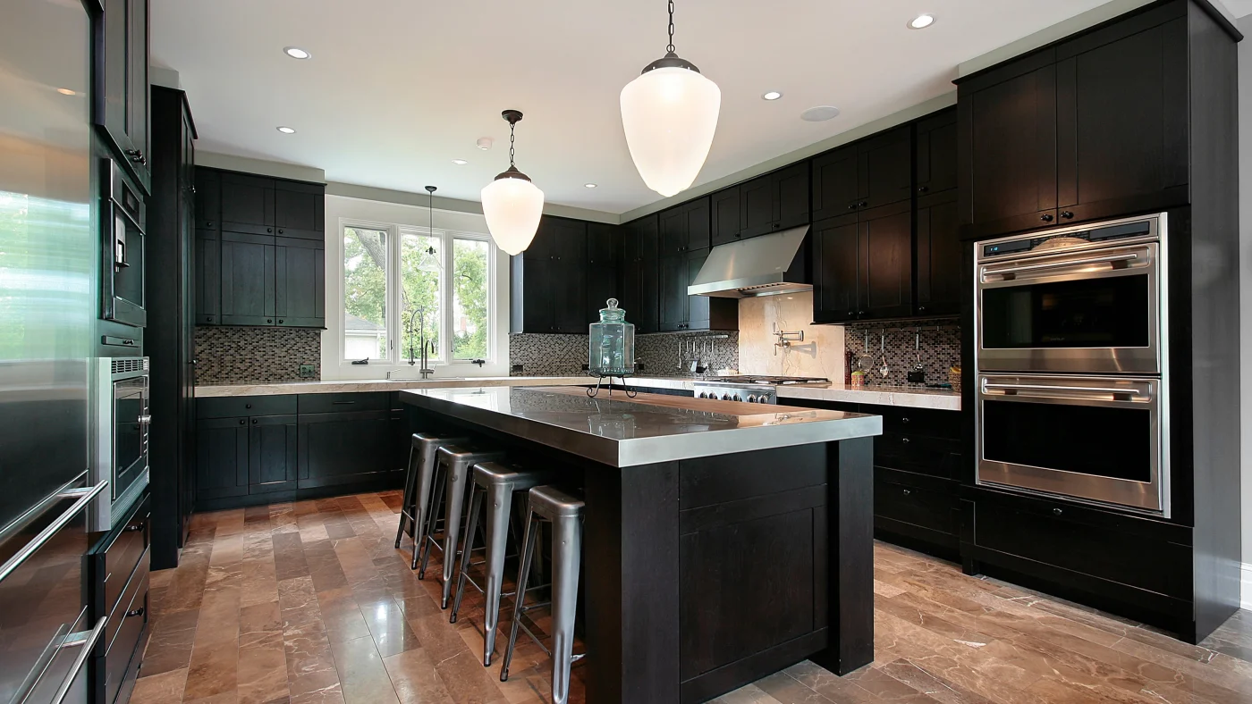 Dark kitchen with black cabinets and dark wood flooring