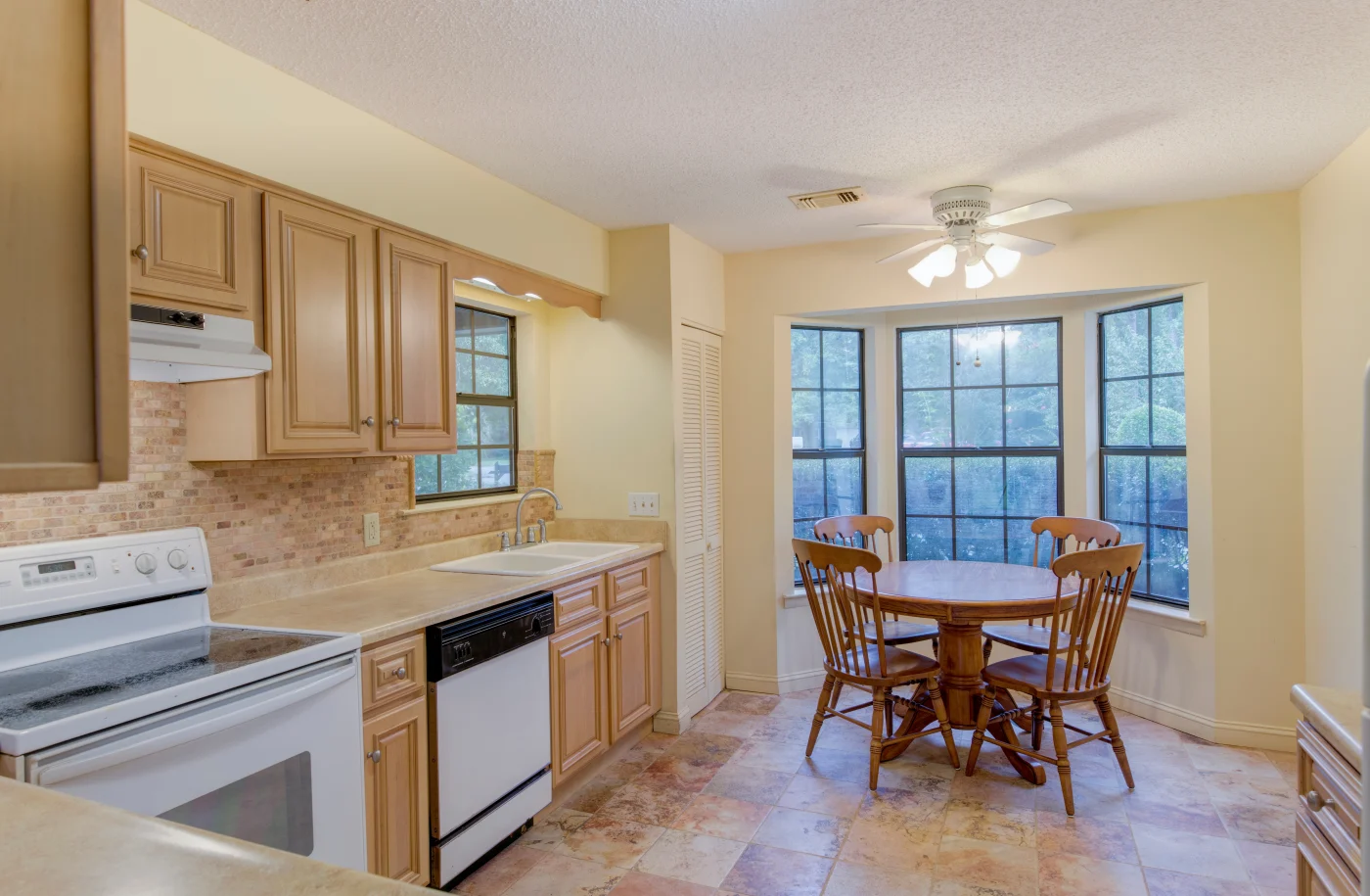 Natural wood cabinets, beige countertop with buttercream walls in kitchen after remodel