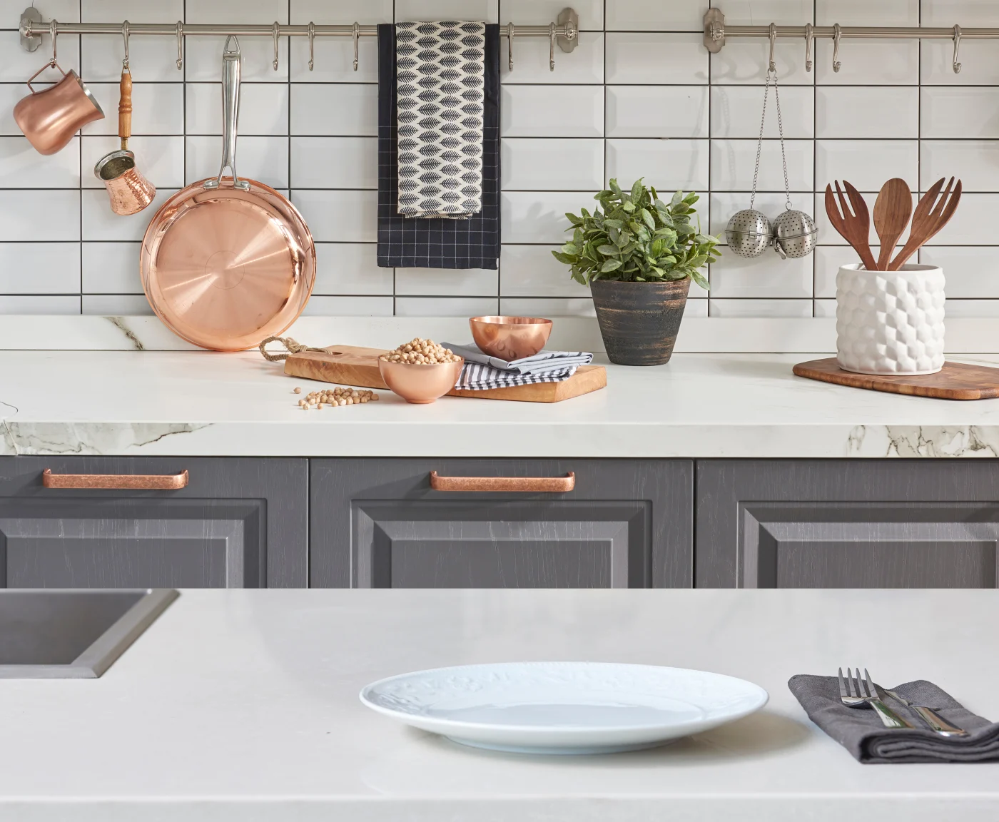 Close-up view of white countertop with gray cabinets and gold hardware in remodeled kitchen