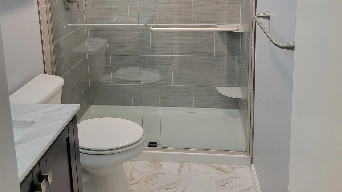 Amazing Full Bathroom Remodels In Georgetown, DE | Mast Contracting Newly remodeled bathroom with a sliding glass shower door, hexagonal tile flooring, a sink with a marble countertop, and subway tile on the shower walls.