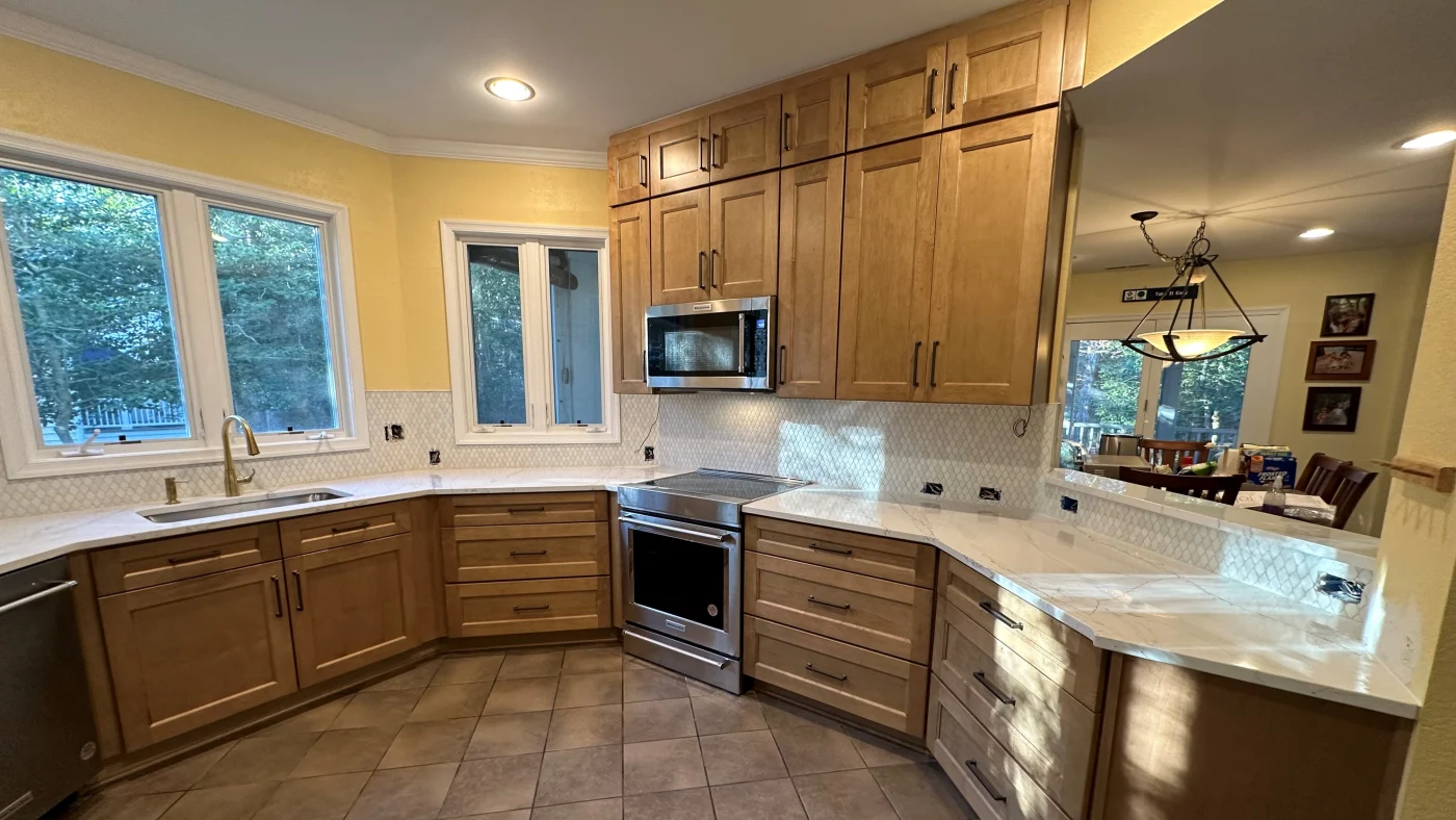 Amazing Kitchen Remodels In Georgetown, DE | Mast Contracting A kitchen with bright wooden cabinets, white marble countertops, and yellow painted walls with small tile backsplashes.