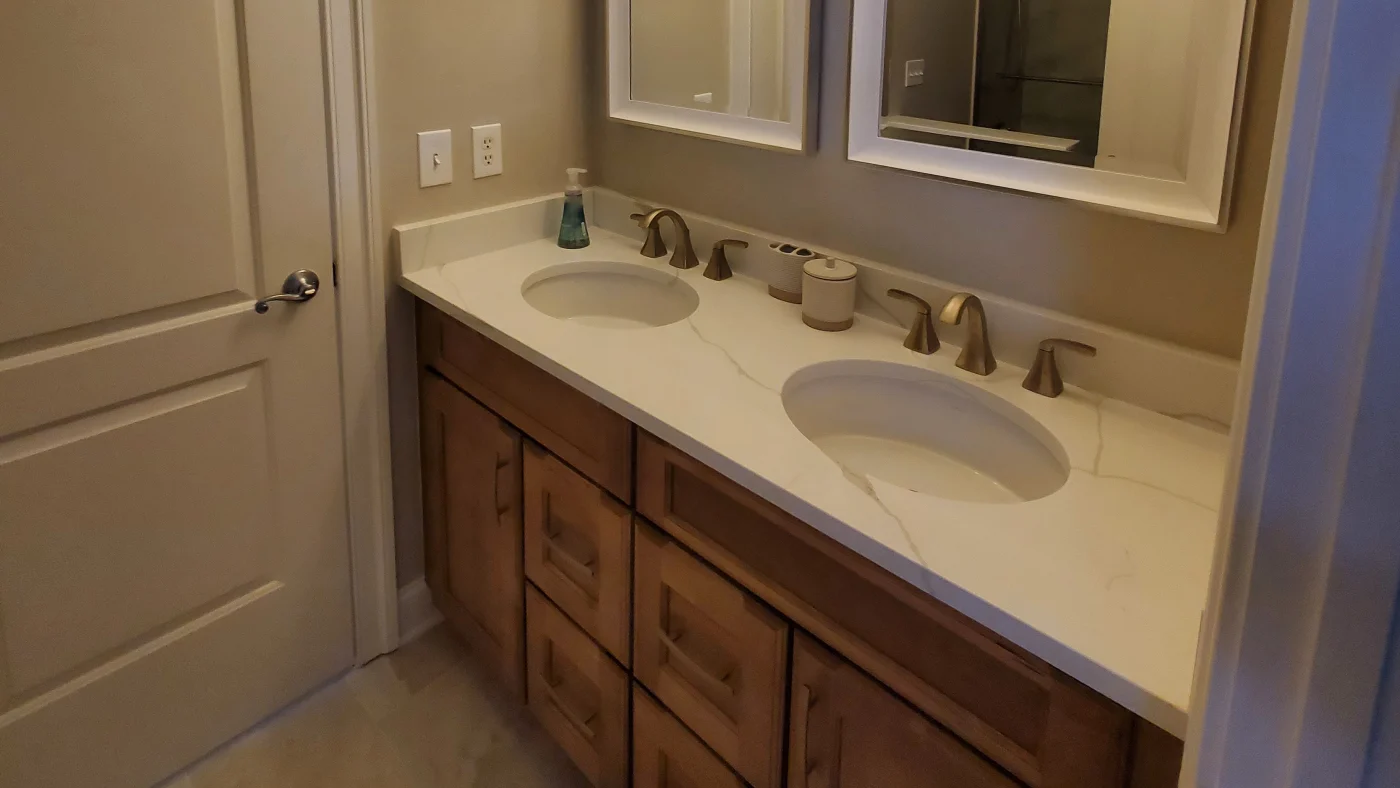 Best 5-Day Bathroom Remodels In Georgetown, DE | Mast Contracting Close-up shot of a dual sink vanity with a white marble countertop and wooden cabinets.