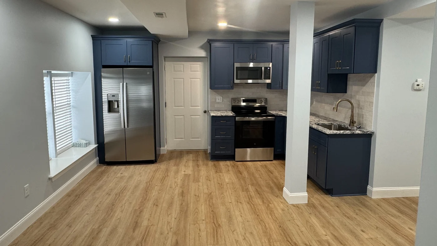 Best Kitchen Remodels In Georgetown, DE | Mast Contracting Newly remodeled open-concept kitchen with wood flooring, dark blue cabinets, and gray and white painted walls with a faux subway tile backsplash.