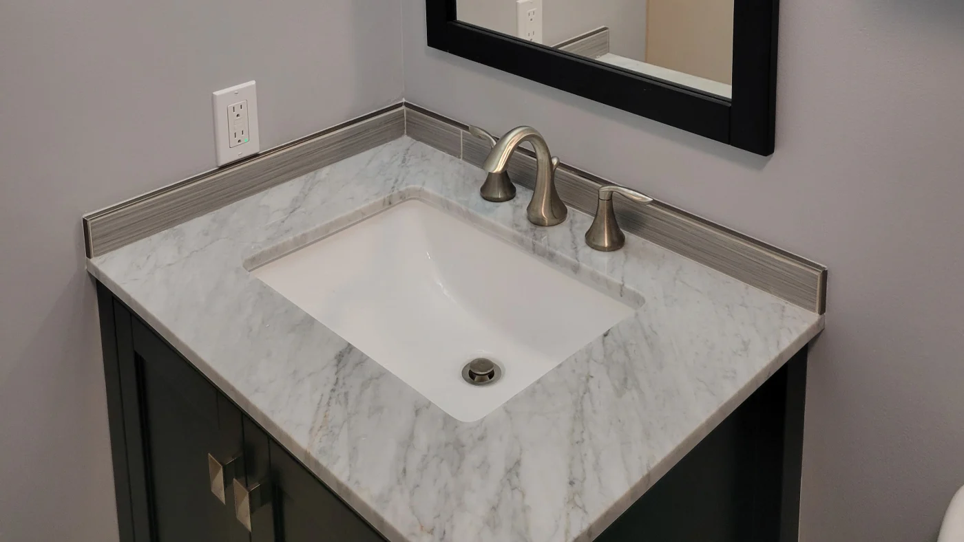 Great 5-Day Bathroom Remodels In Georgetown, DE | Mast Contracting A small bathroom sink with a gray marble countertop and black cabinet underneath.