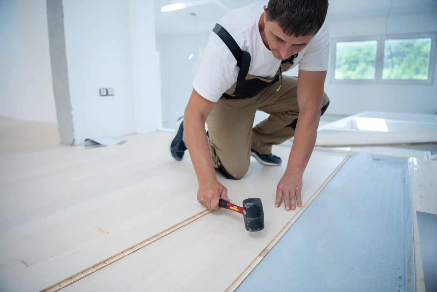 Professional Worker Installing New Laminated Wooden Floor Professional Worker Installing New Laminated Wooden Floor