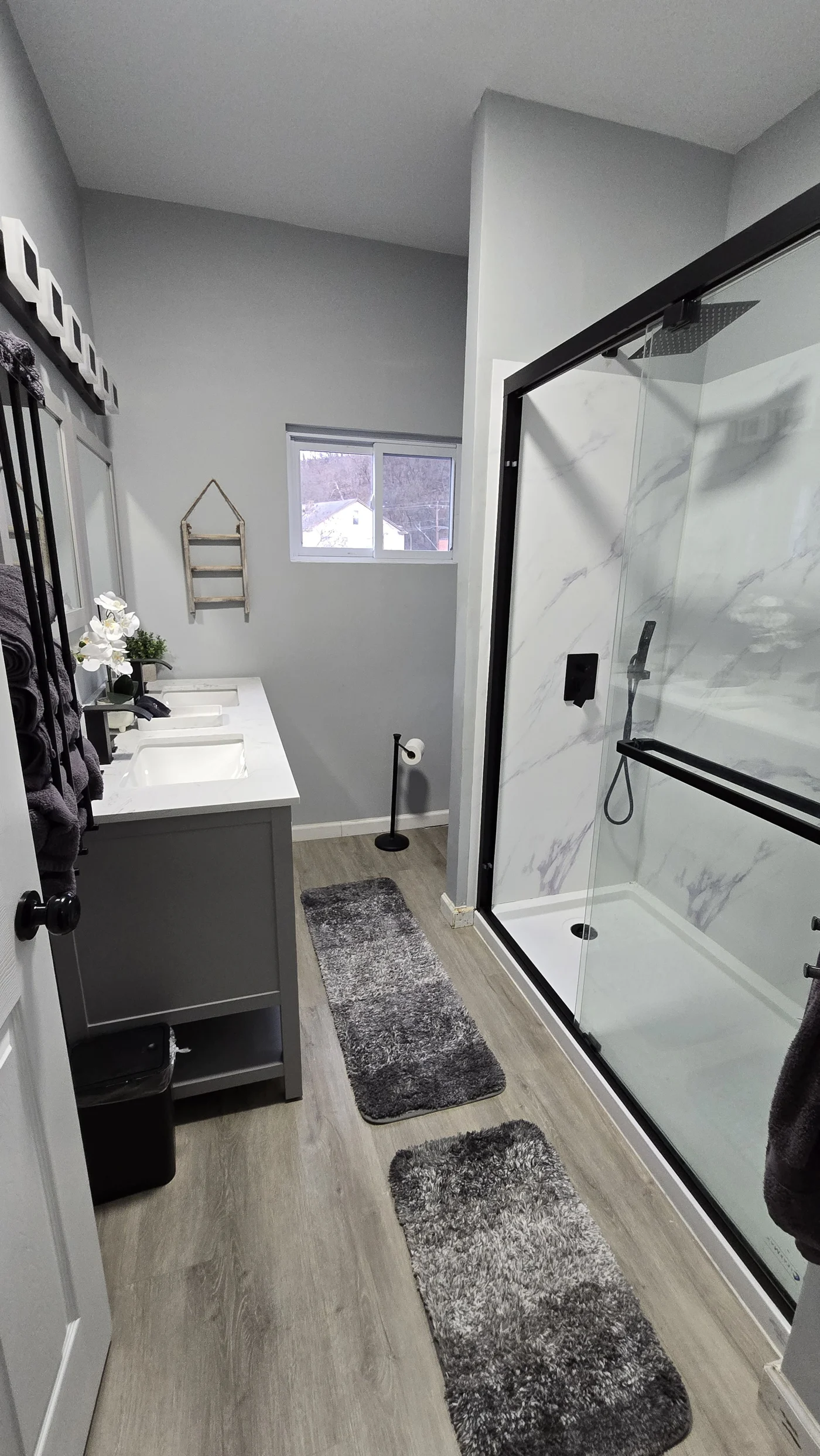 Modern Bathroom Interior Design, Clean And Simple Bathroom Interior Showcasing A Functional Bathtub, Modern Sink, And Neatly Arranged Amenities For A Refreshing And Inviting Atmosphere A bathroom with wood floors, dark gray cabinets, and black-framed shower doors