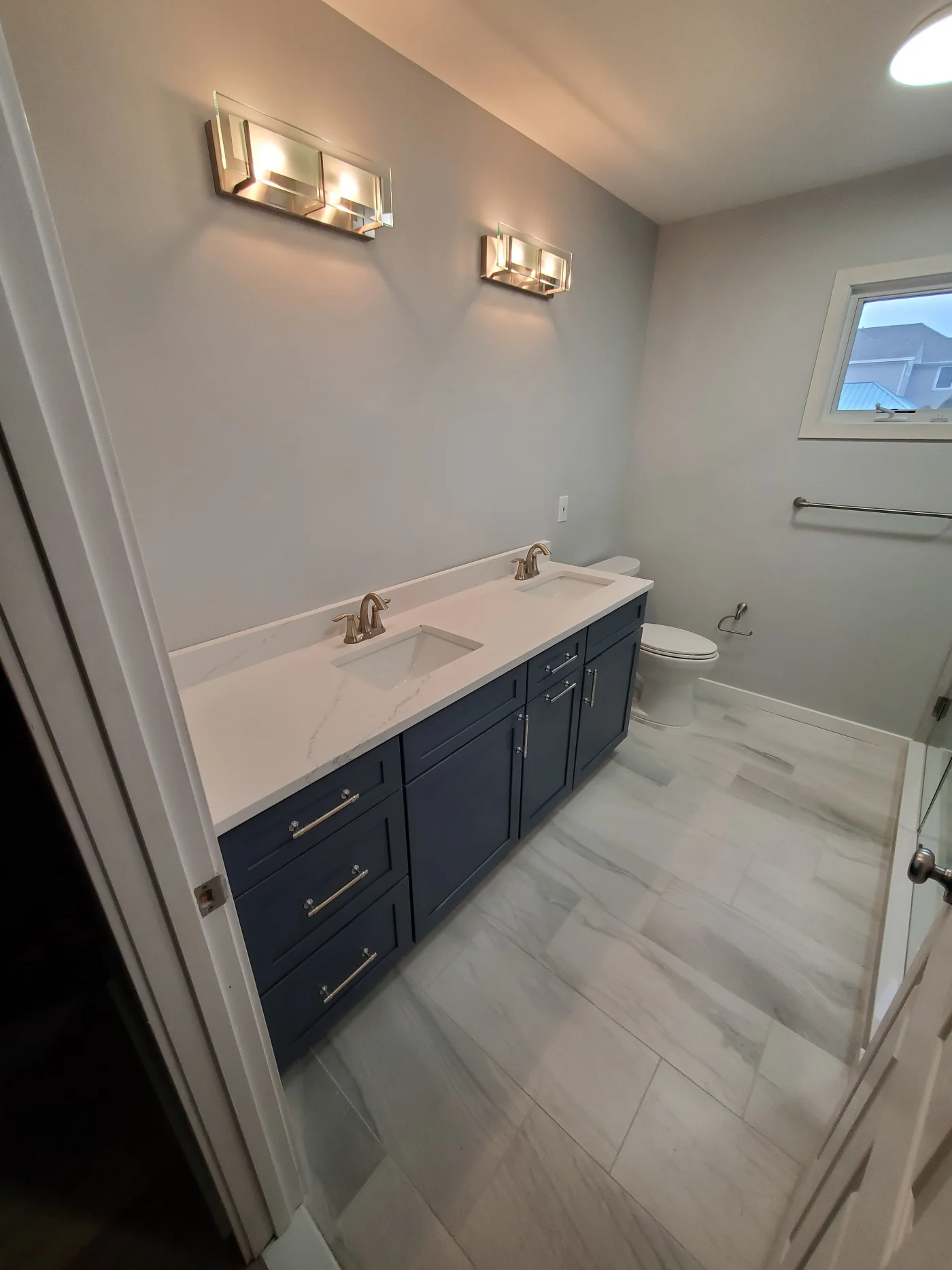 Impressive Bathroom Remodel | Selbyville, DE | Mast Contracting A stylish bathroom remodel featuring a navy blue double-sink vanity with white quartz countertops