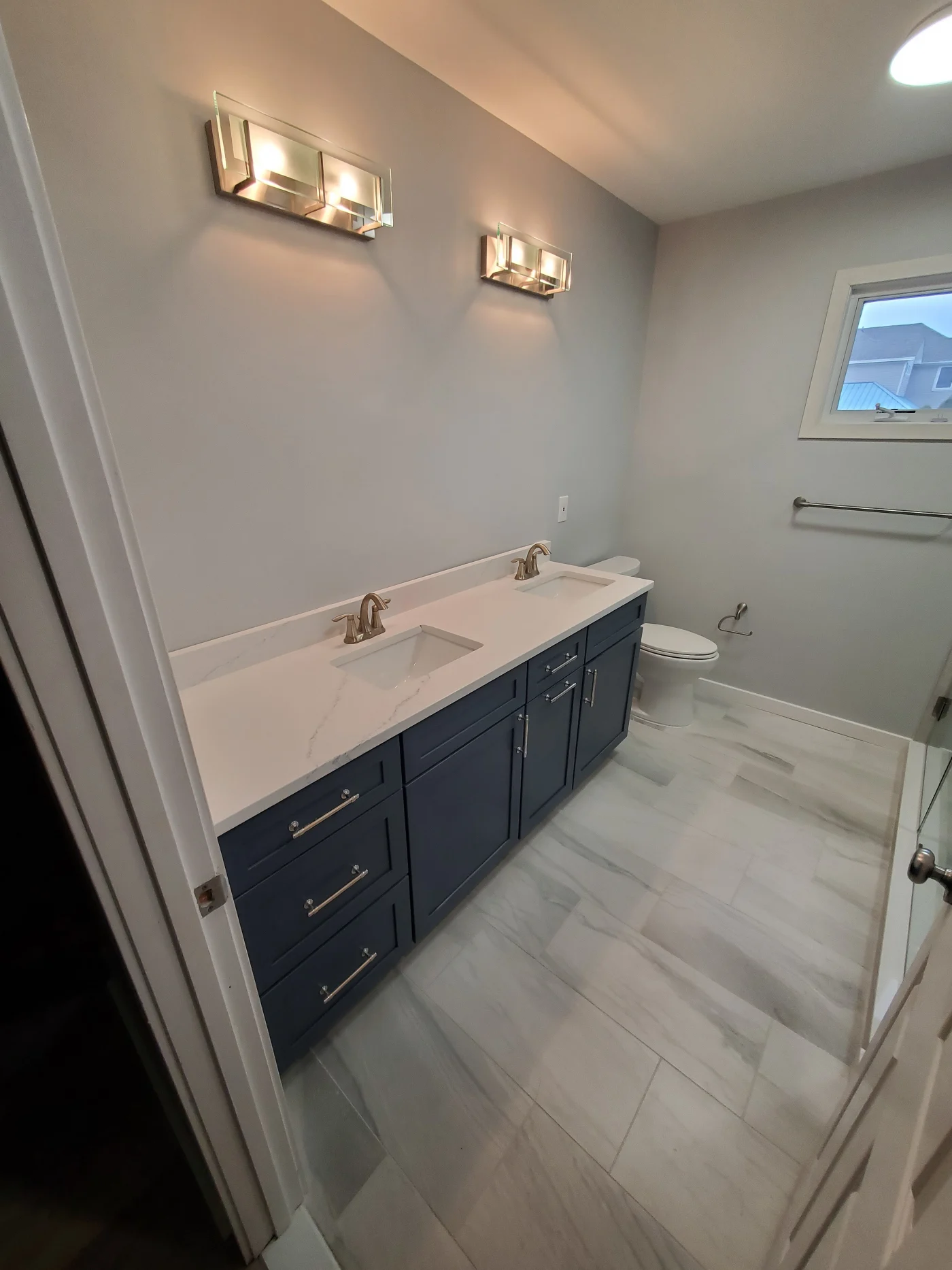 Efficient 5-Day Bathroom | Frankford, DE | Mast Contracting 5-day bathroom remodel featuring a double vanity with blue shaker cabinets, quartz countertops, and modern wall-mounted lighting.