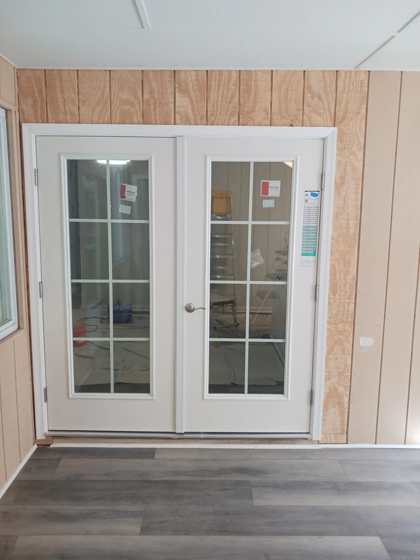 A white French door installation with divided glass panes and updated trim.