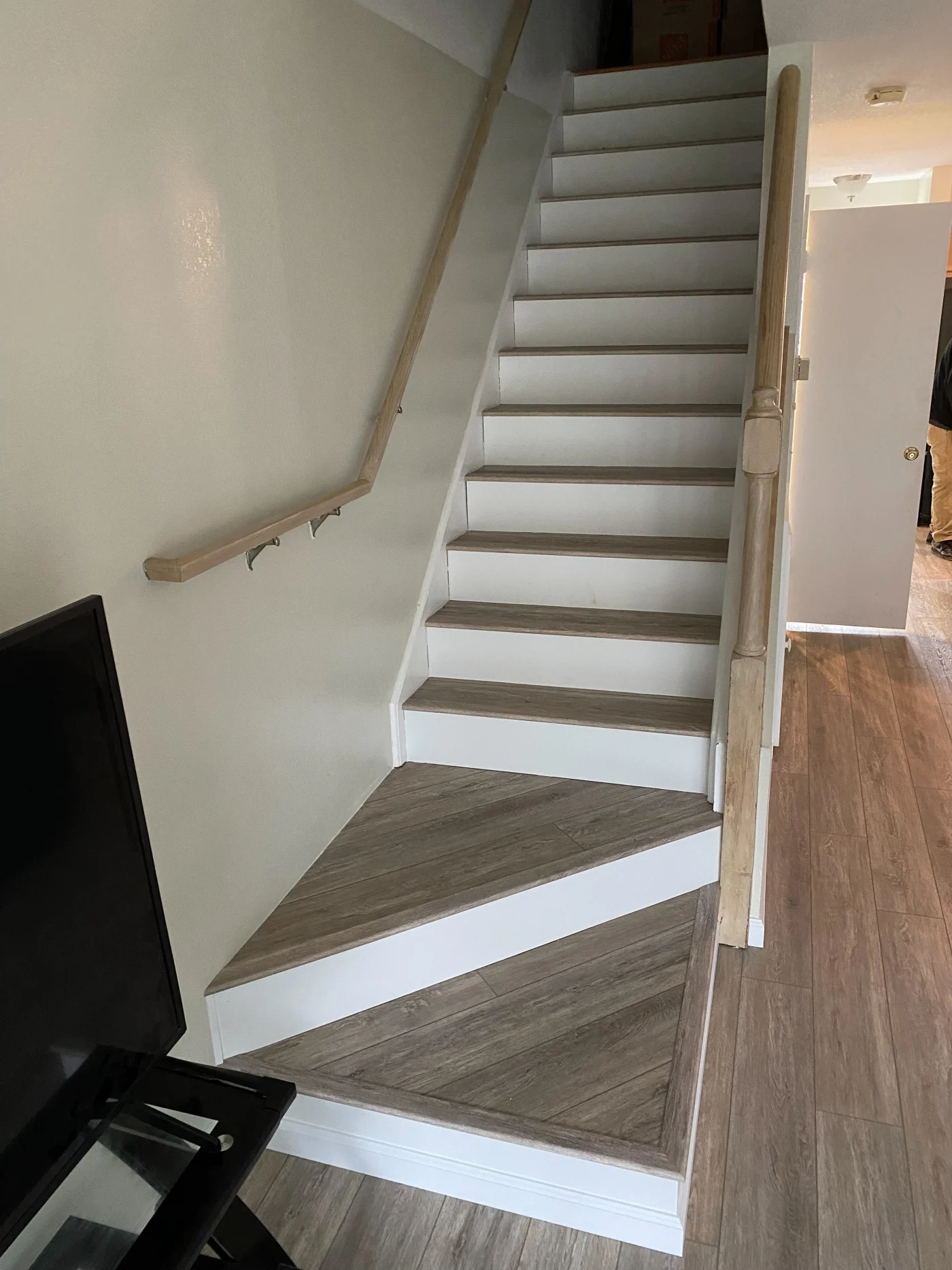 High Value Interior Remodeling | Dagsboro, DE | Mast Contracting Updated staircase with light wood-look treads and matching vinyl plank flooring, featuring crisp white risers and a corner landing.