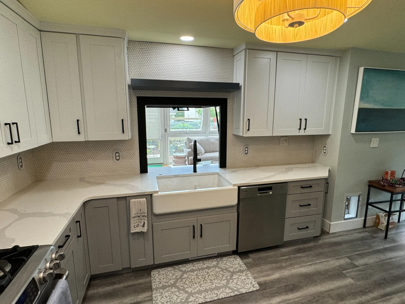 Outstanding Kitchen Remodel Bethany Beach De Mast Contracting Modern U-shaped kitchen remodel with white shaker cabinets, black hardware, quartz countertops, and a farmhouse sink beneath a large window.