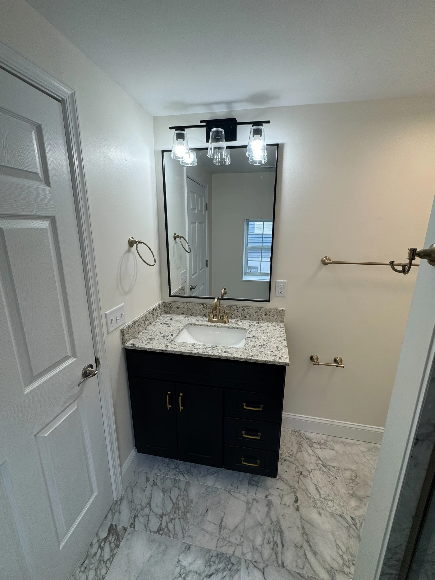 Professional Full Bathroom Remodel | Dagsboro, DE | Mast Contracting Elegant full bathroom remodel featuring a dark vanity with brass hardware, speckled granite countertop, rectangular undermount sink, and framed mirror.