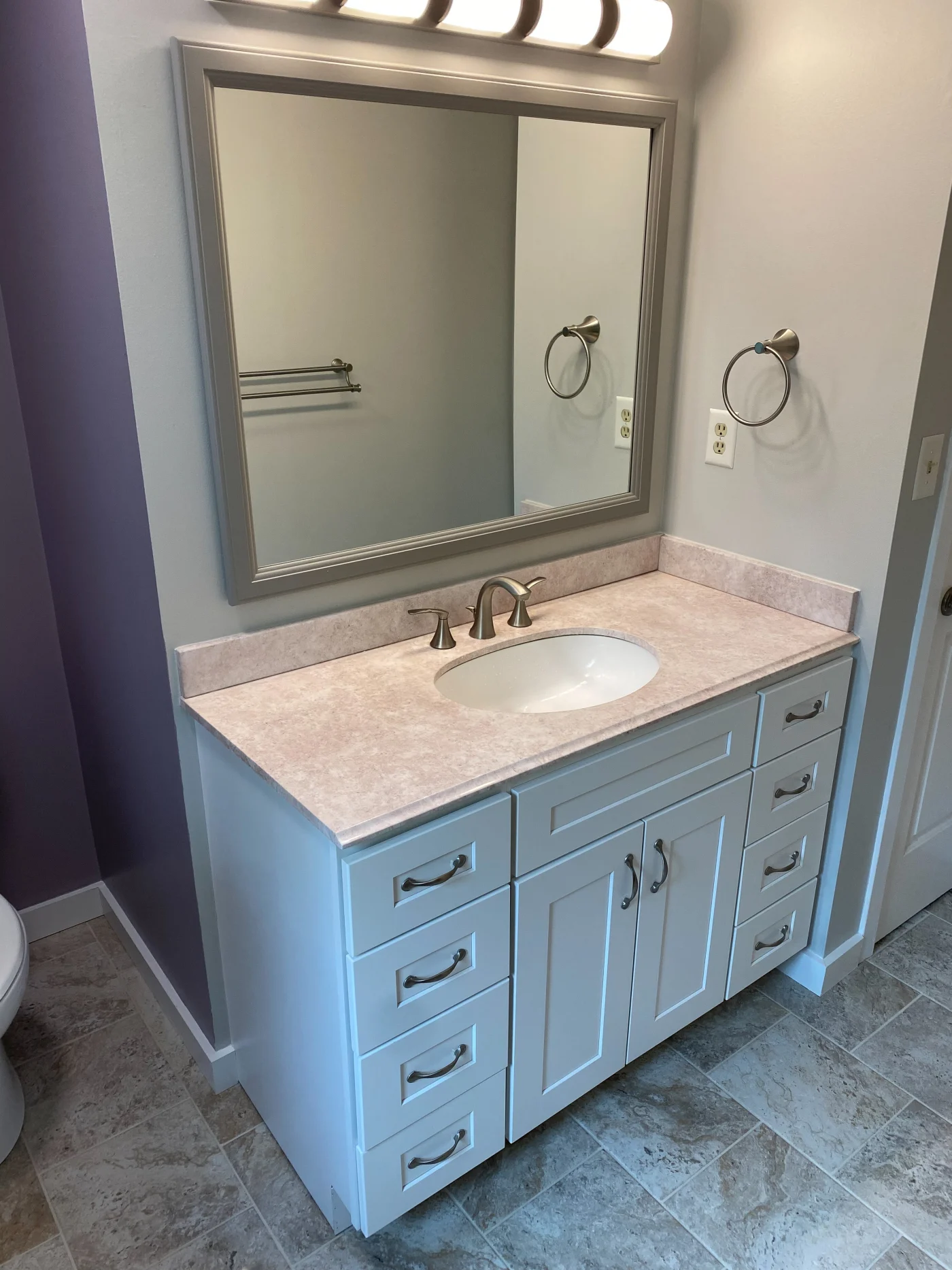 Beautiful Full Bathroom Remodel | Rehoboth, DE | Mast Contracting Remodeled bathroom with a light blue vanity, stone-look countertop, undermount sink, framed mirror, brushed-nickel faucet, and gray tile floor.